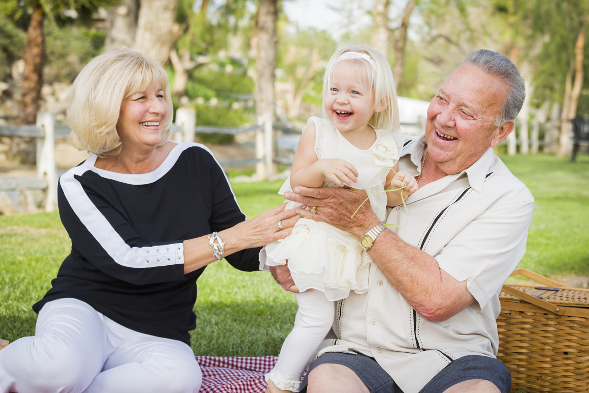 Affectionate Granddaughter and Grandparents Playing Outside At The Park.