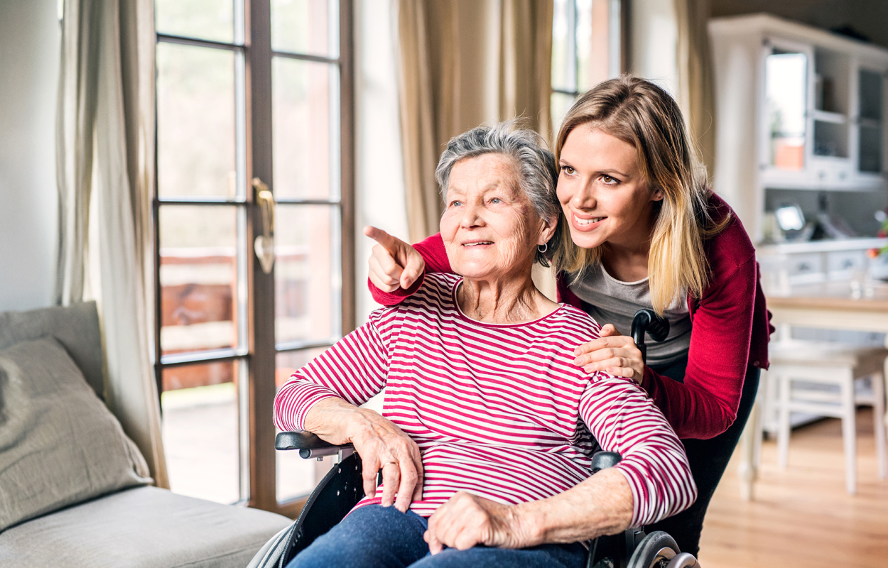 An elderly grandmother in wheelchair with an adult granddaughter at home.