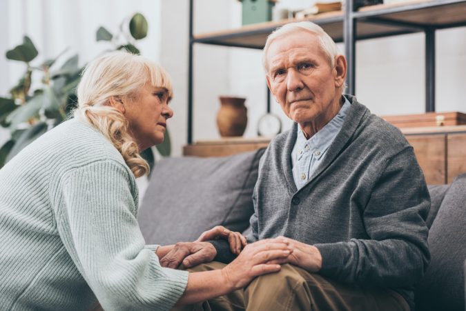 retired wife looking at senior husband in living room